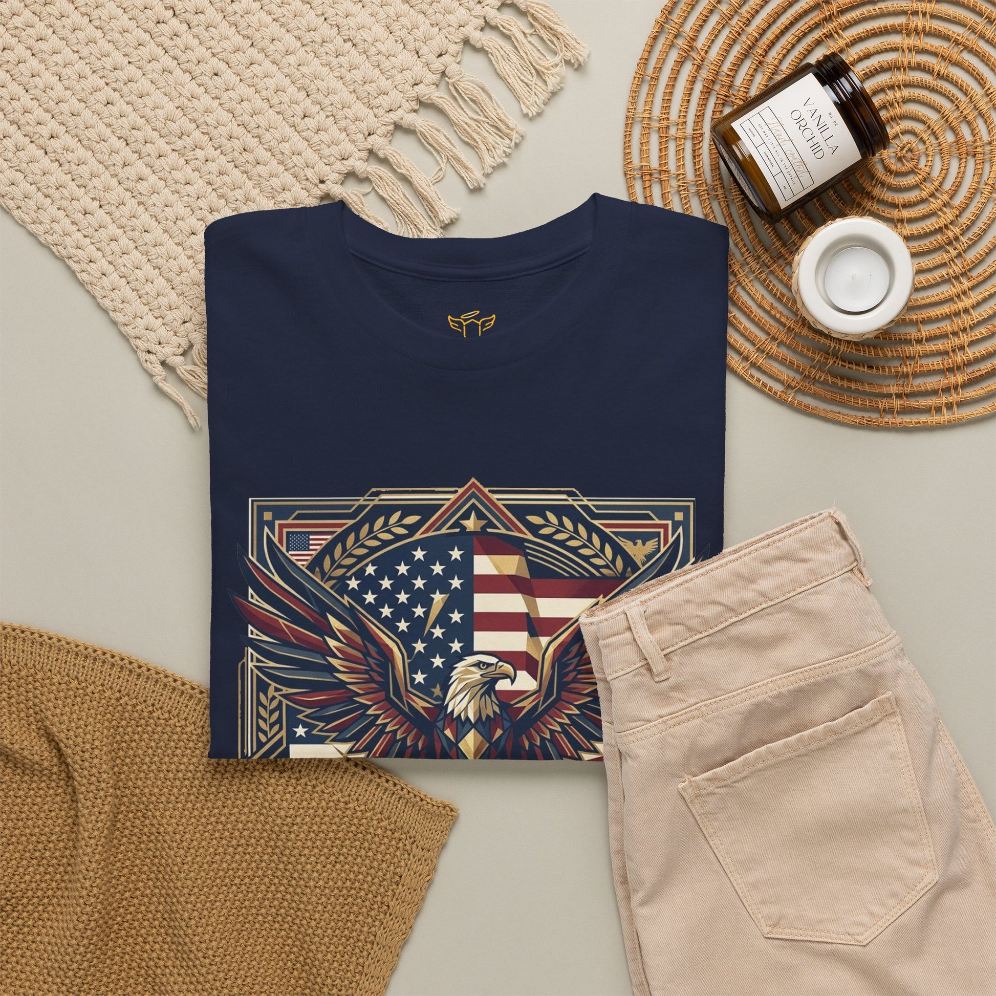250 Years of Freedom Eagle T-Shirt, Navy blue t-shirt with an eagle and flag design on a neutral surface with pants and decor items.
