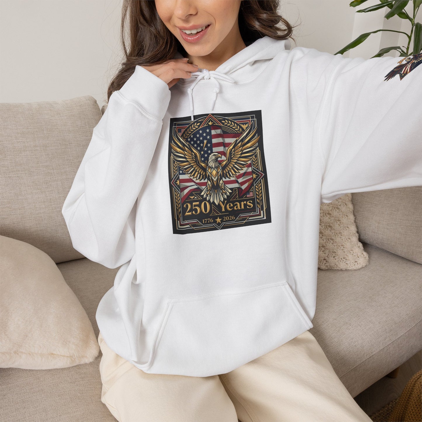 Person wearing a white hoodie with an eagle and flag design, sitting on a couch. America 250 Years of Freedom Hoodie — USA 250th ANNIVERSARY Patriotic Hoodie