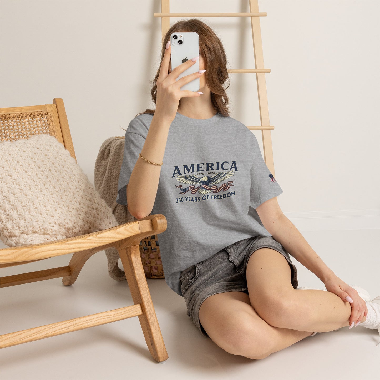 America 250 Years of Freedom T-Shirt — USA 250th ANNIVERSARY T-shirt, Person wearing a gray t-shirt with a skull and crossed swords design, sitting on the floor.