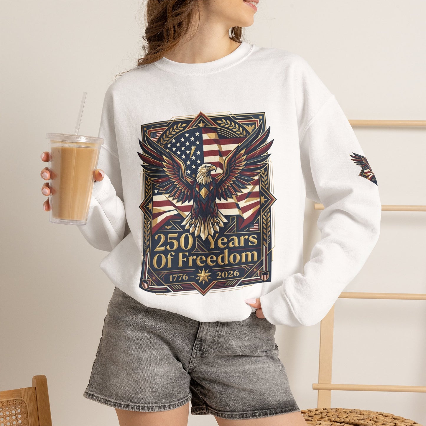 USA 250th ANNIVERSARY Crewneck Sweatshirt , Person wearing a white sweatshirt with an eagle and American flag design, holding a drink.