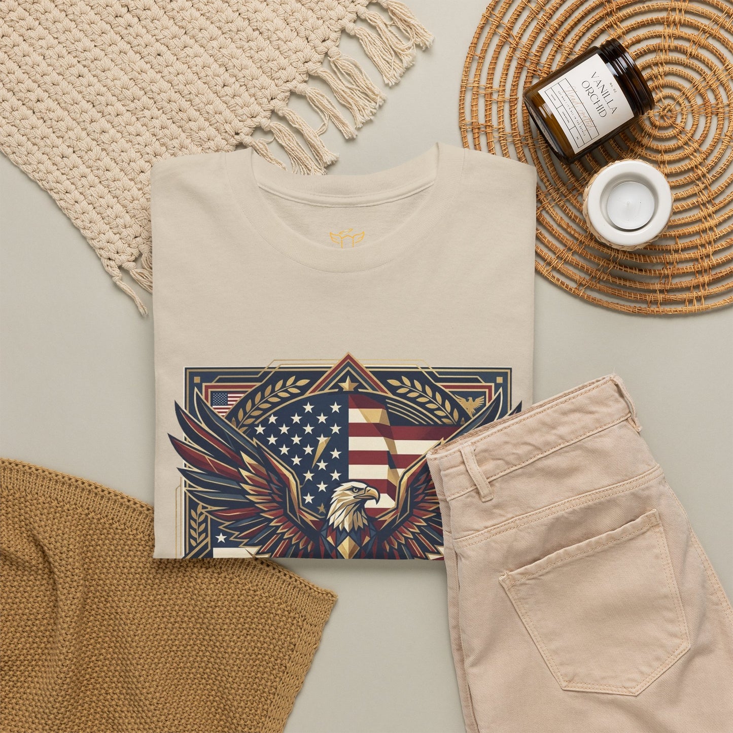 Beige t-shirt with eagle and flag design, beige pants, and decorative items on a light surface.