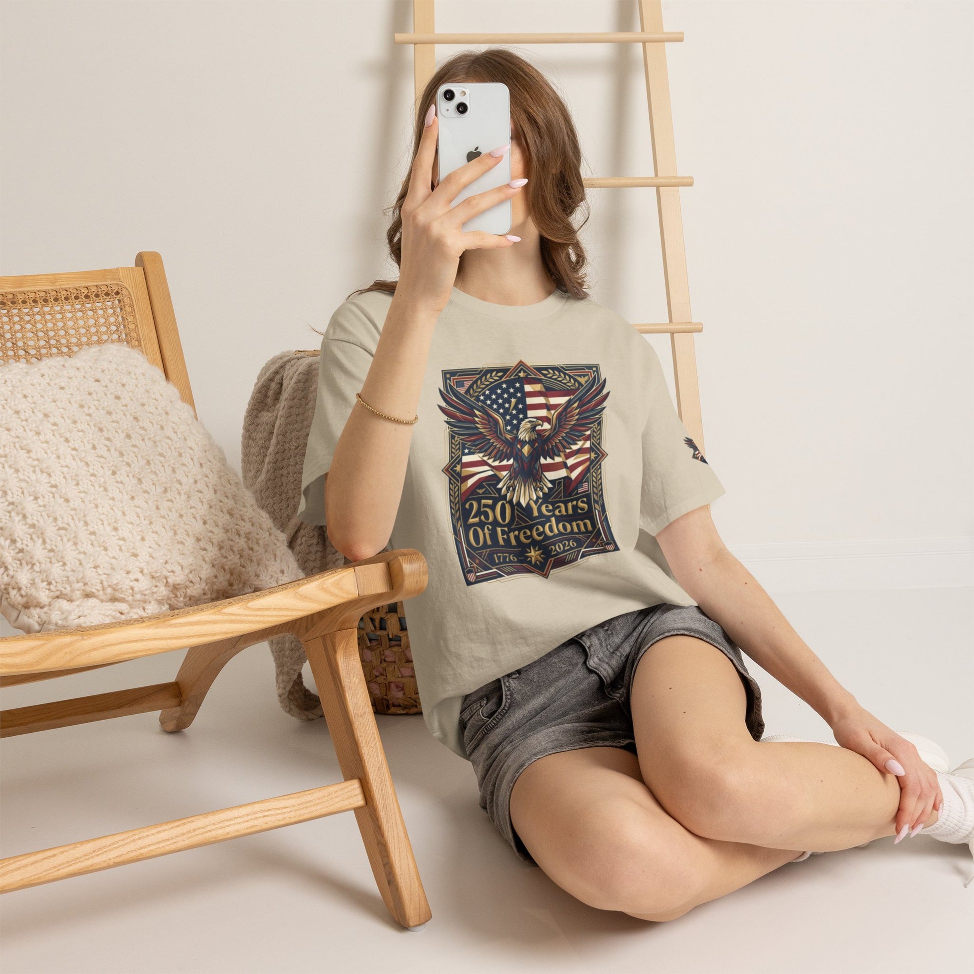 250 Years of Freedom Eagle T-Shirt, Person sitting on the floor holding a phone, wearing a graphic t-shirt with an eagle design.