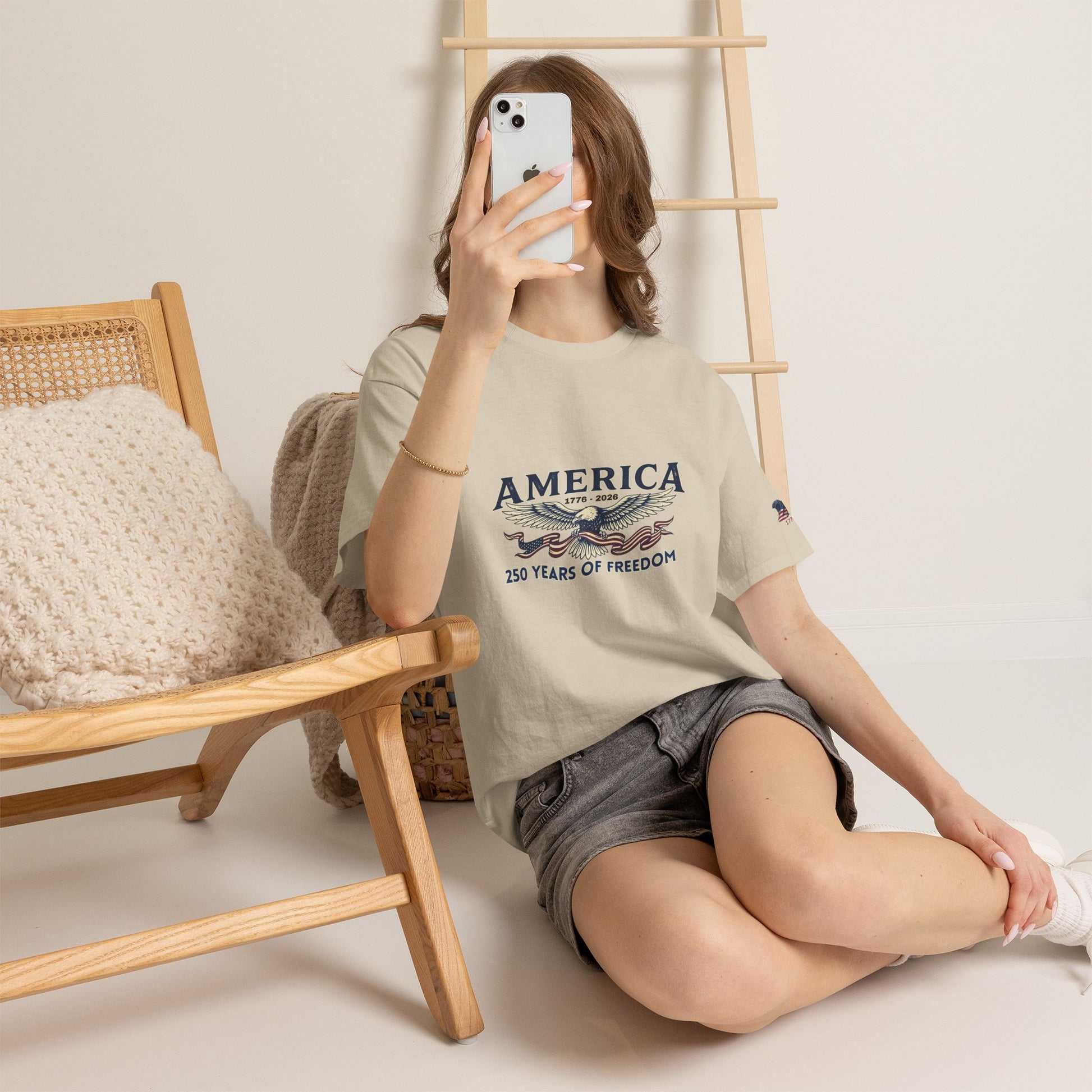 America 250 Years of Freedom T-Shirt — USA 250th ANNIVERSARY T-shirt, Person wearing a t-shirt with 'America' text sitting on the floor.