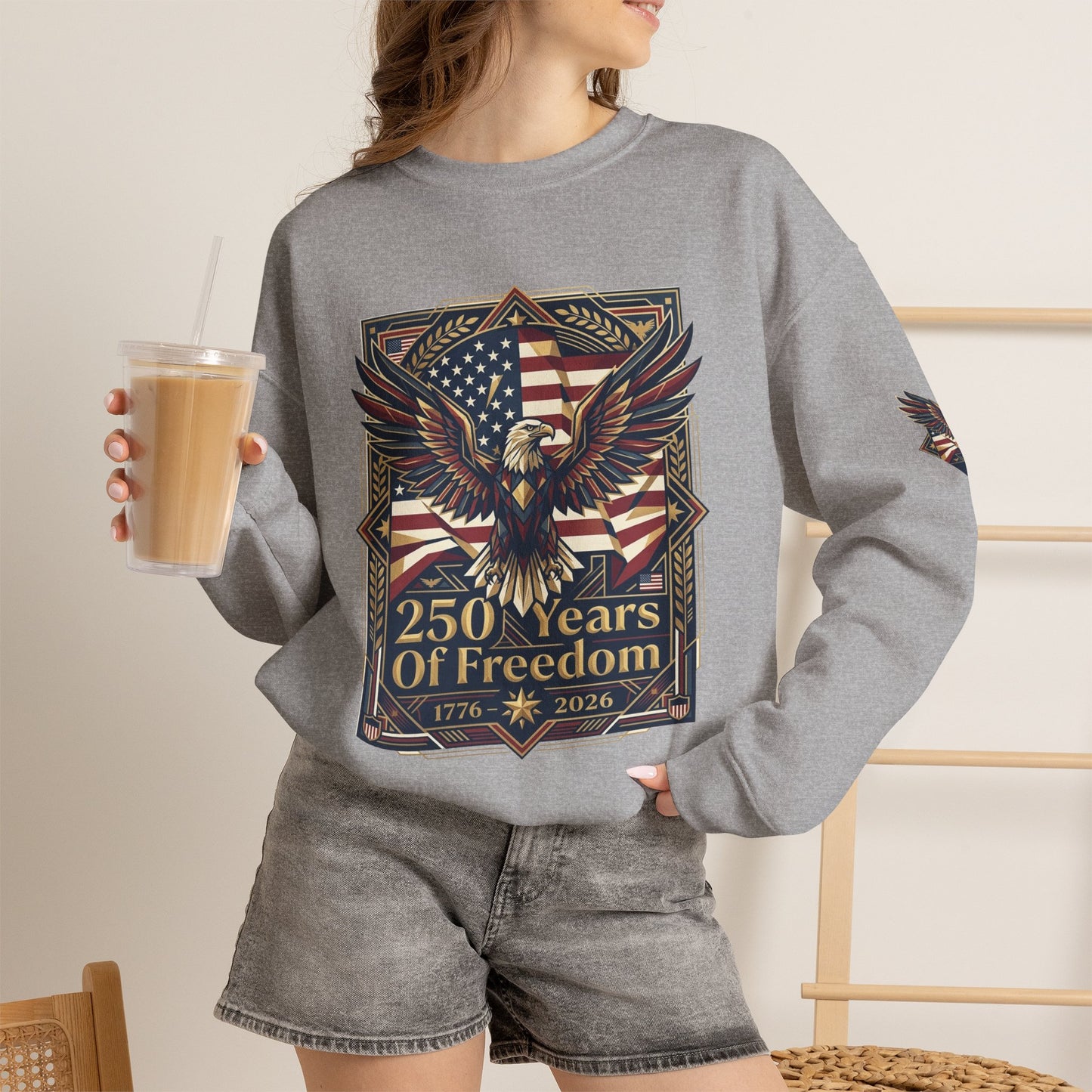 USA 250th ANNIVERSARY Crewneck Sweatshirt , Person wearing a gray sweatshirt with an eagle and American flag design, holding a drink.