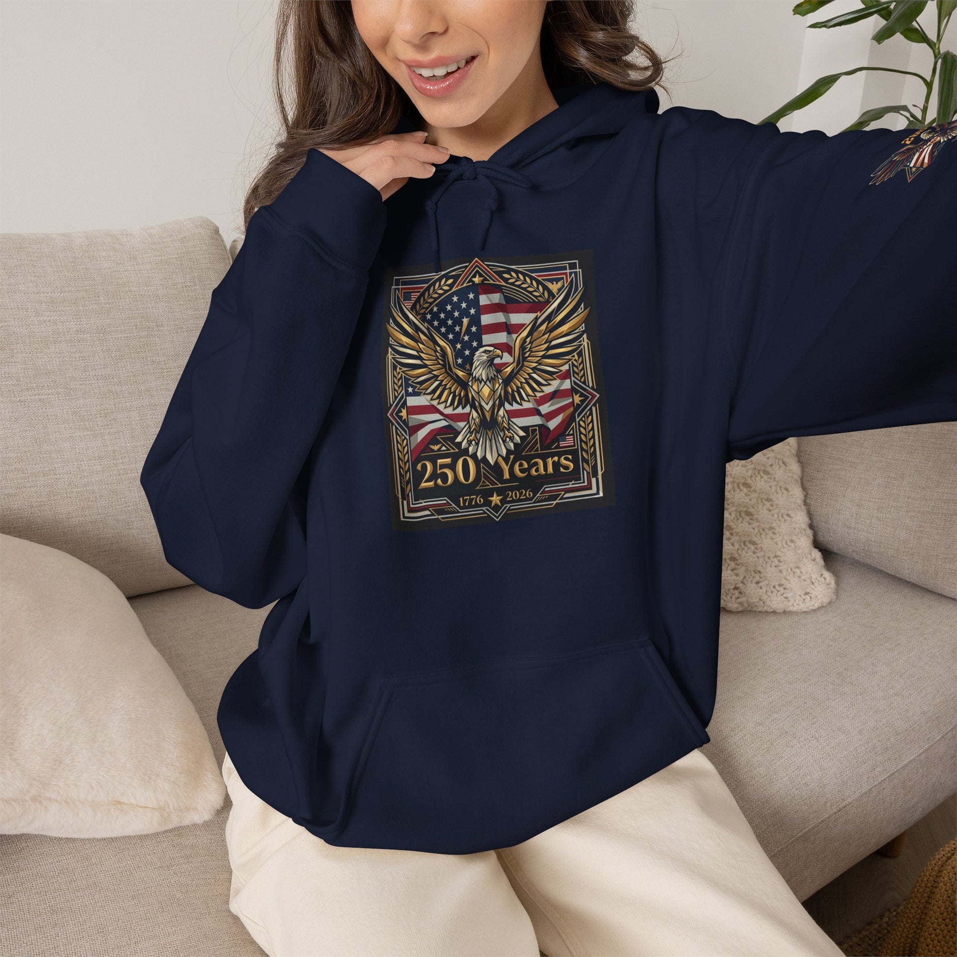 America 250 Years of Freedom Hoodie — USA 250th ANNIVERSARY Patriotic Hoodie, Person wearing a navy blue hoodie with an eagle and flag design, sitting on a couch.