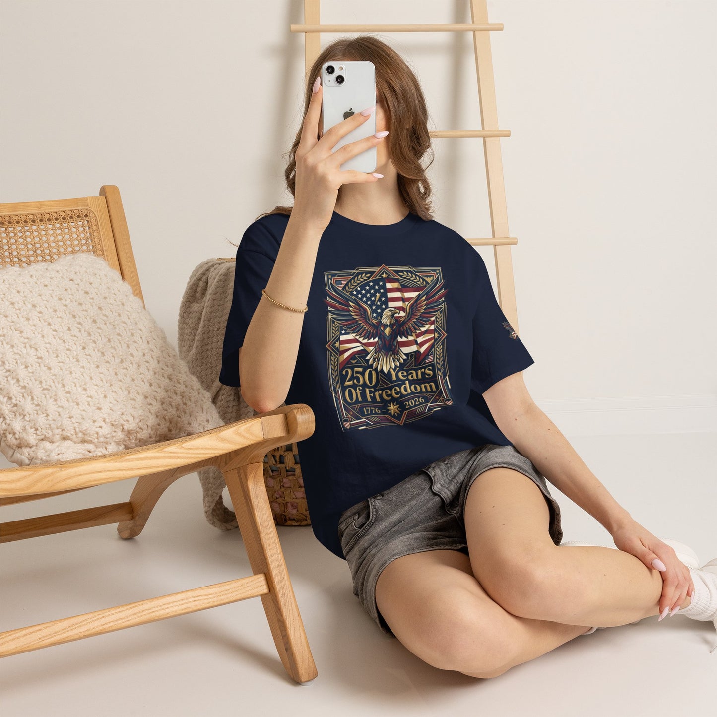 250 Years of Freedom Eagle T-Shirt, Person wearing a black t-shirt with colorful graphic design, sitting on the floor with a phone.