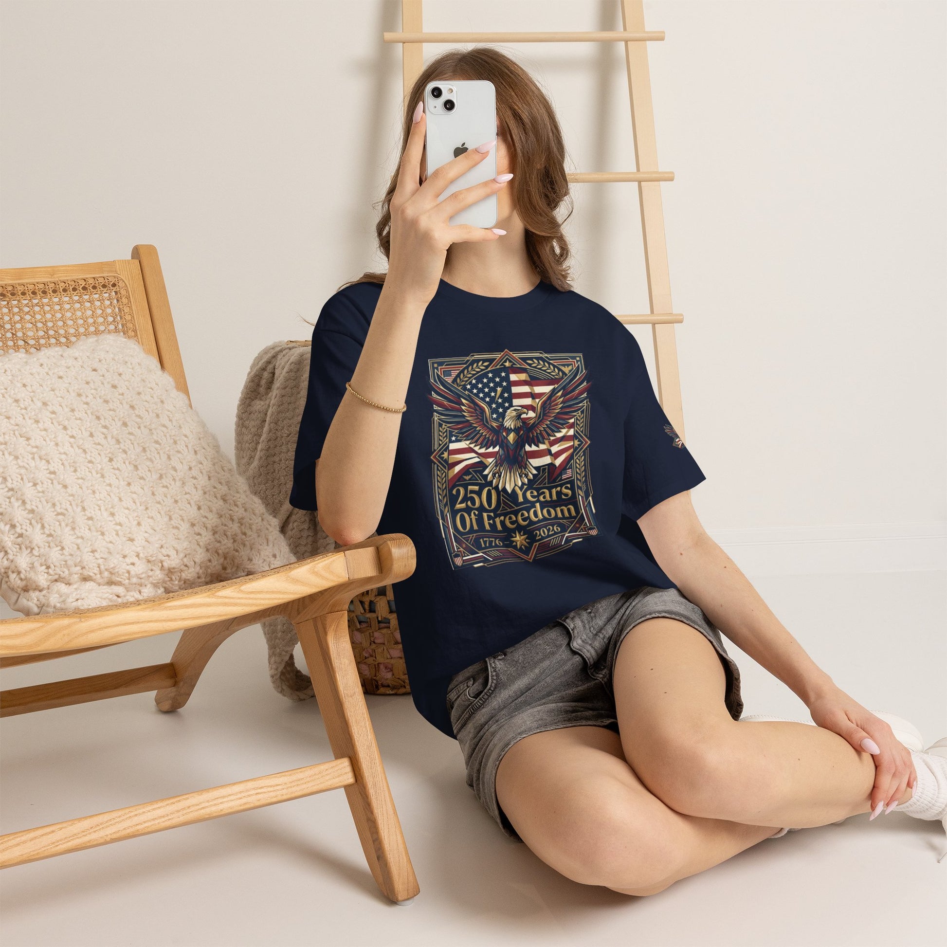 250 Years of Freedom Eagle T-Shirt, Person wearing a black t-shirt with colorful graphic design, sitting on the floor with a phone.