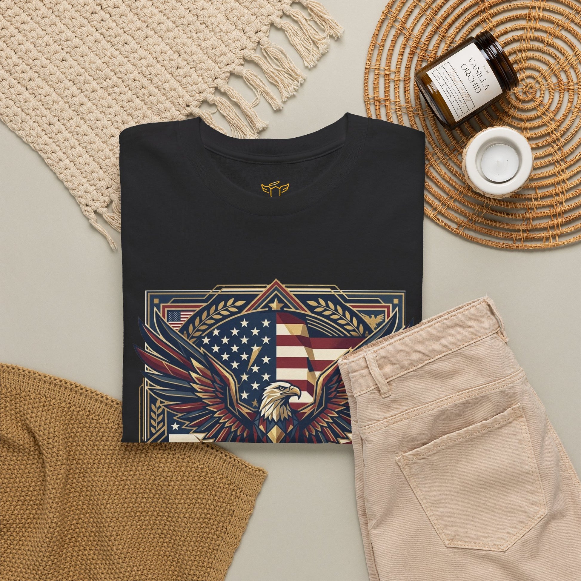 Black t-shirt with eagle and American flag design on a neutral surface with accessories.